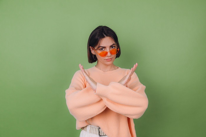 Young Woman In Casual Peach And Orange Eyeglasses Sweater Isolated On Green Olive Background Serious Showing Stop Gesture With Crossed Hands Copy Space