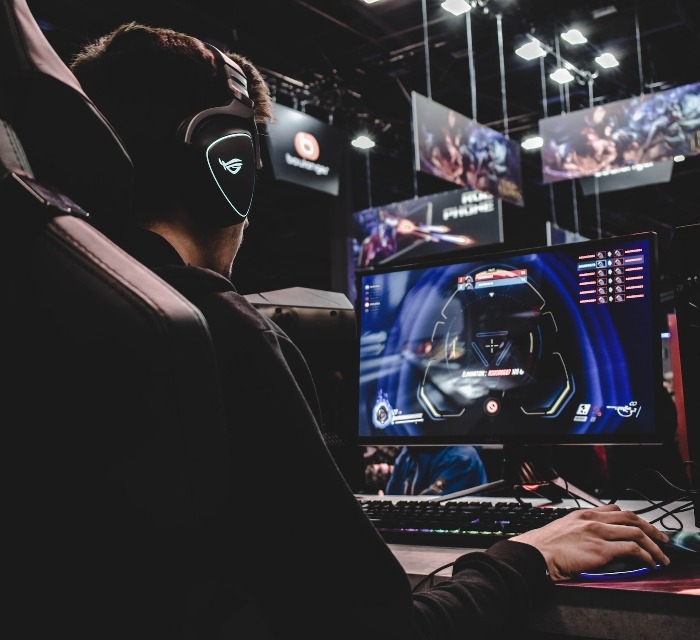 Person wearing headphones playing games on a PC