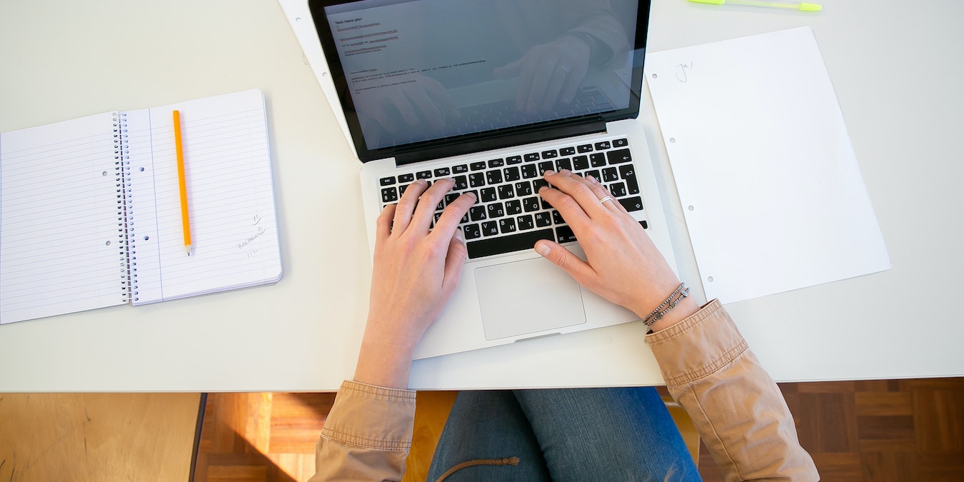 Man Working On Computer With Notebook On The Side