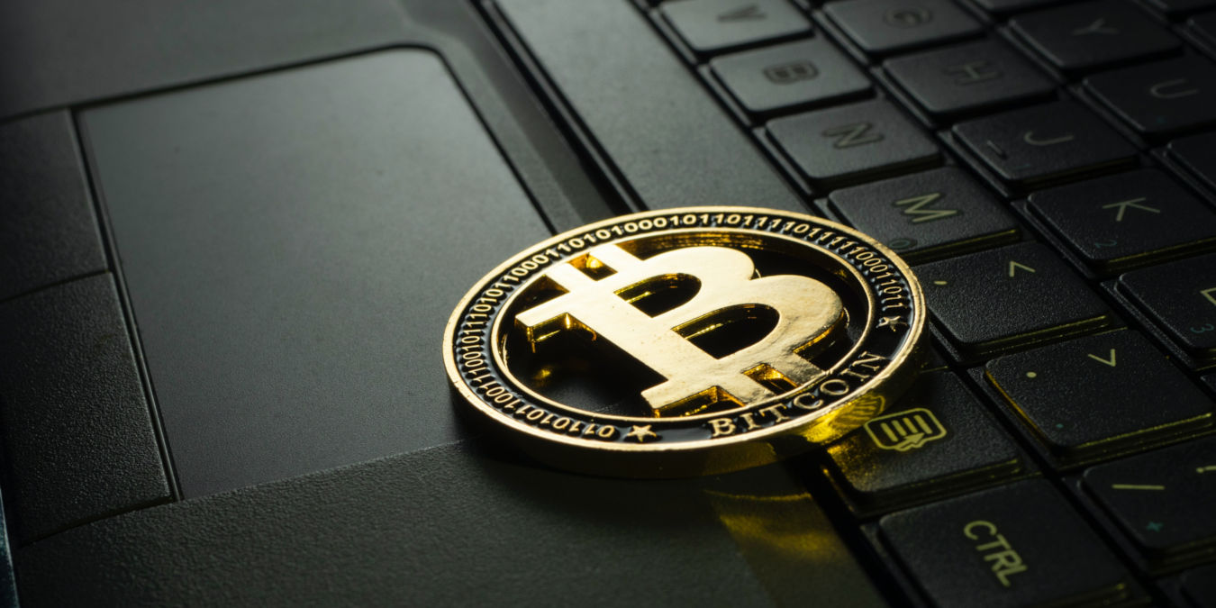 A metal Bitcoin coin on top of a laptop keyboard.