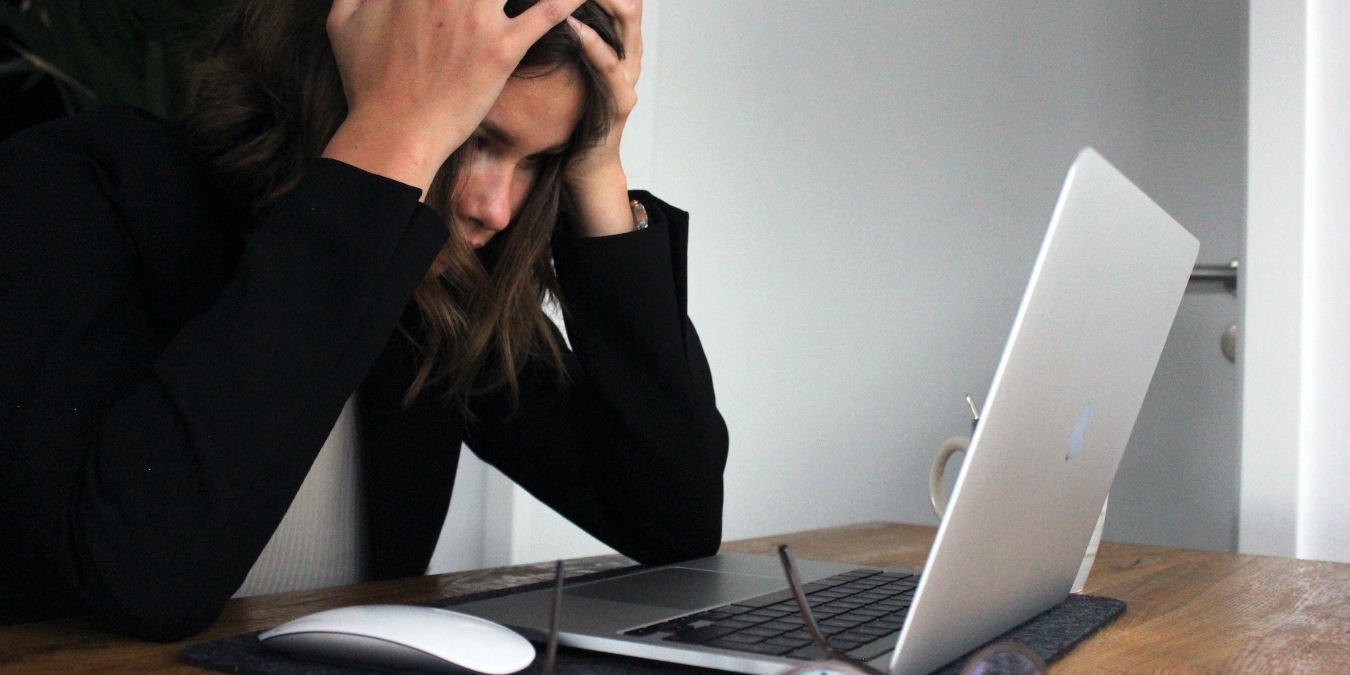 woman in black shirt frustrated at her laptop computer