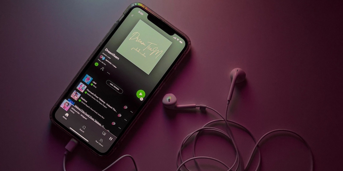 Spotify app on black smartphone with earphones on a desk
