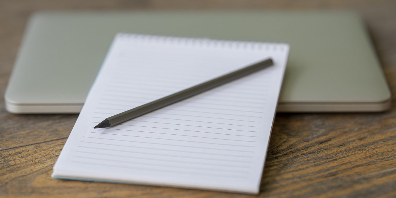 Notepad, pen, and laptop