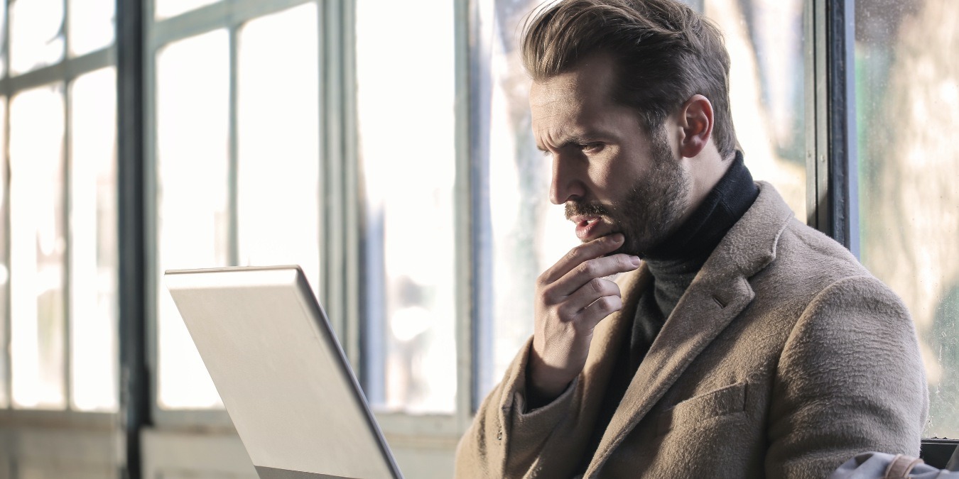 Man holding his chin facing a laptop