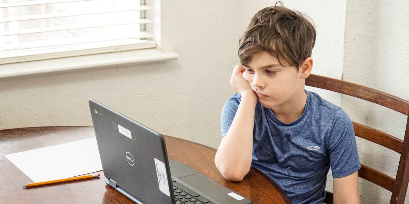 Boy in blue t-shirt using a Windows laptop