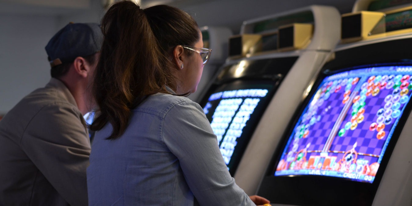 A photograph of two people playing an arcade game.