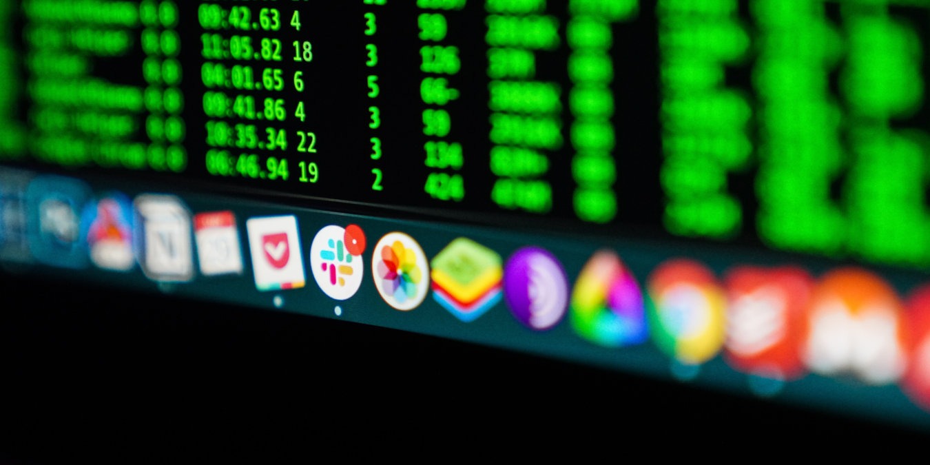 A photograph of a monitor screen with a dock full of icons.