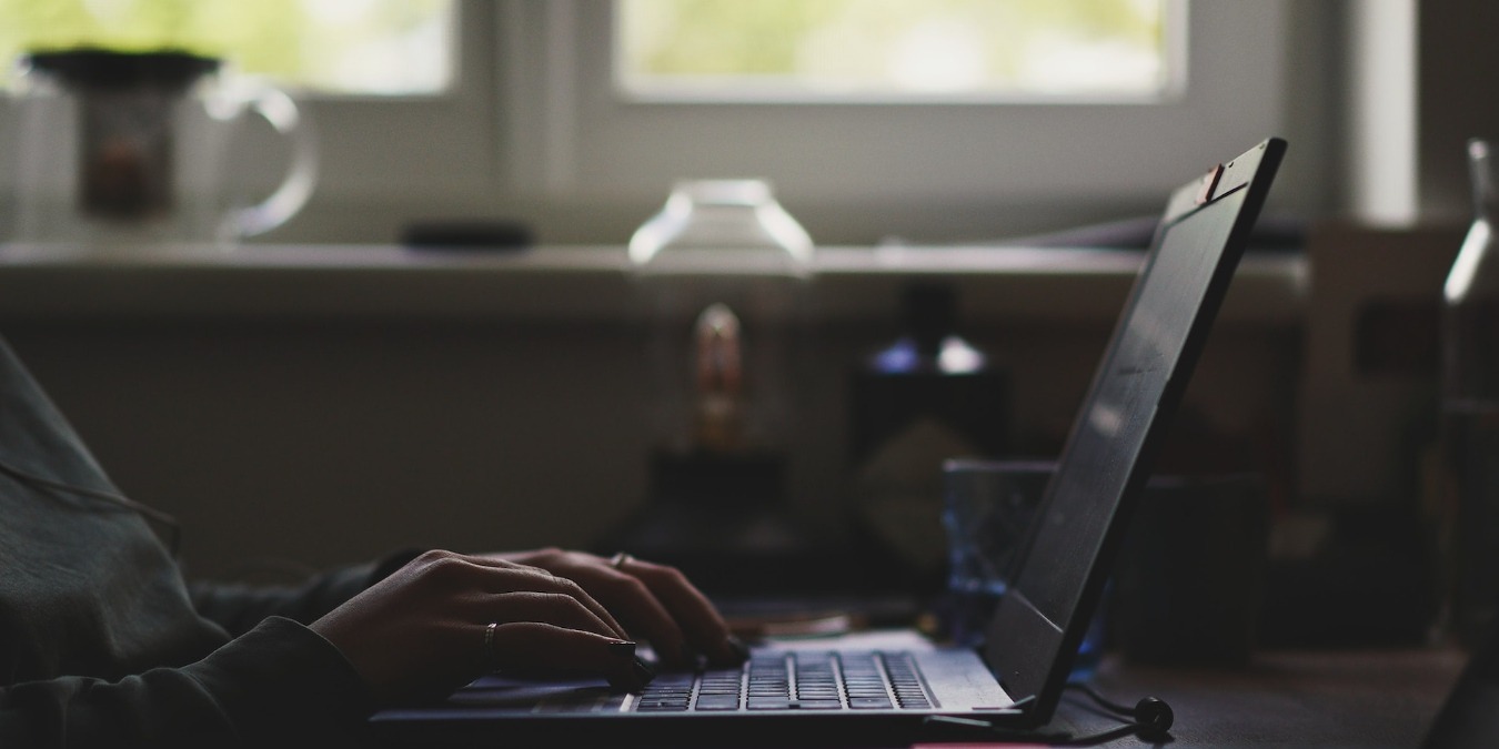 Person using a laptop near a window during daytime