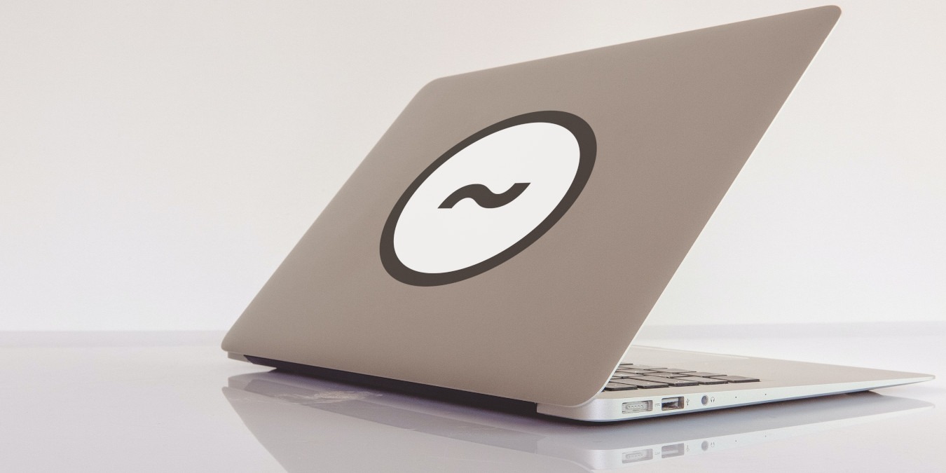 A photograph of a half-open laptop on a reflective table.