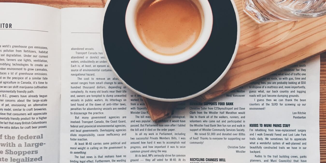 Magazine showing columns on a table with coffee