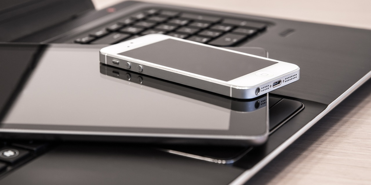 This photo shows a laptop, iPad, and smartphone stacked on top of another.