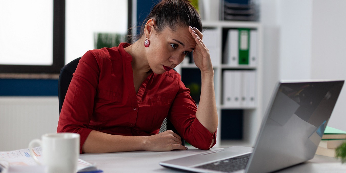 Tired Businesswoman Sitting At Startup Business Desk Looking At Laptop Screen.