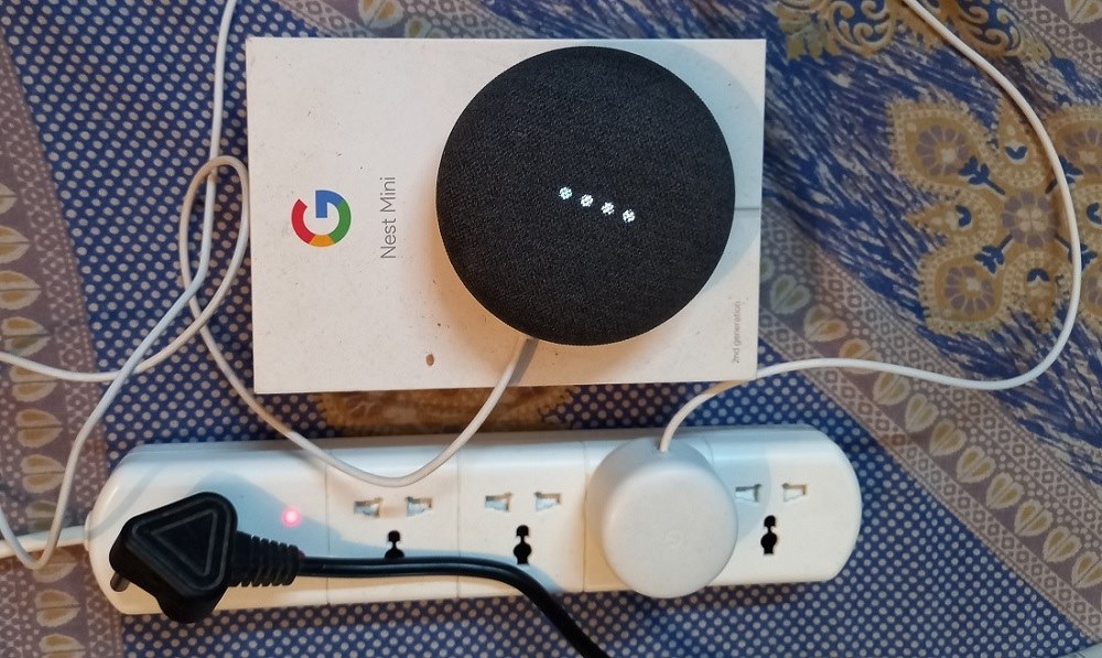 Nest Mini 2nd generation speaker with its white lights on and in listening mode.