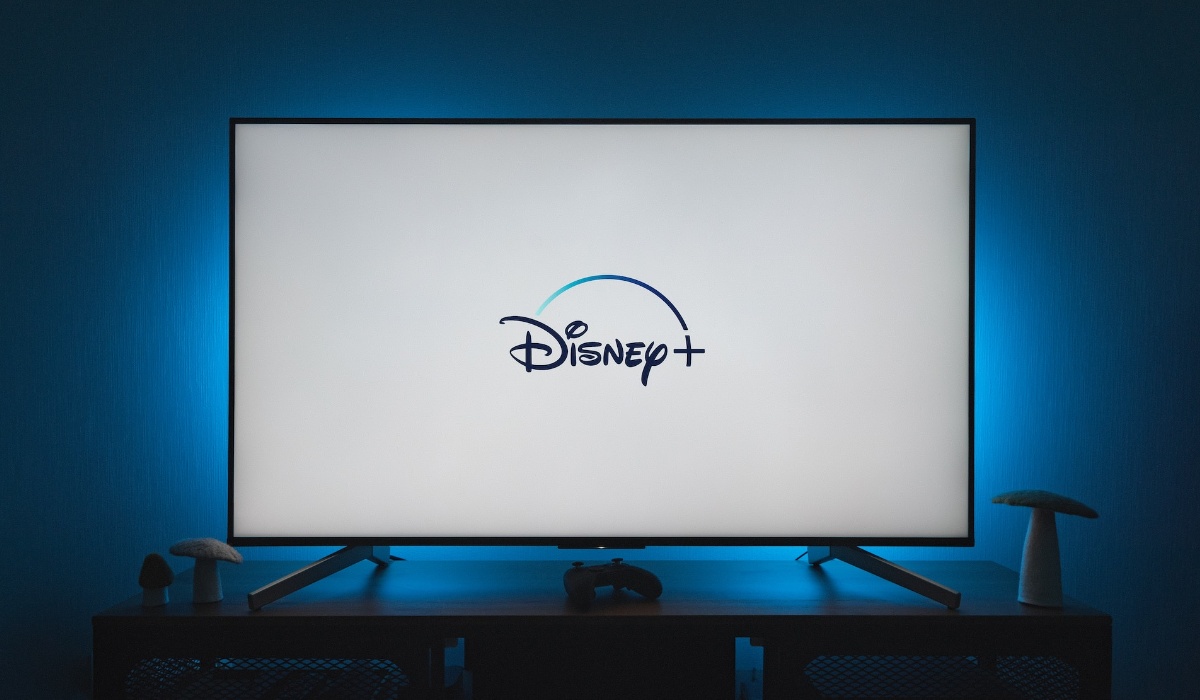 Large screen TV on top of a stand with blue light behind it in a dark room
