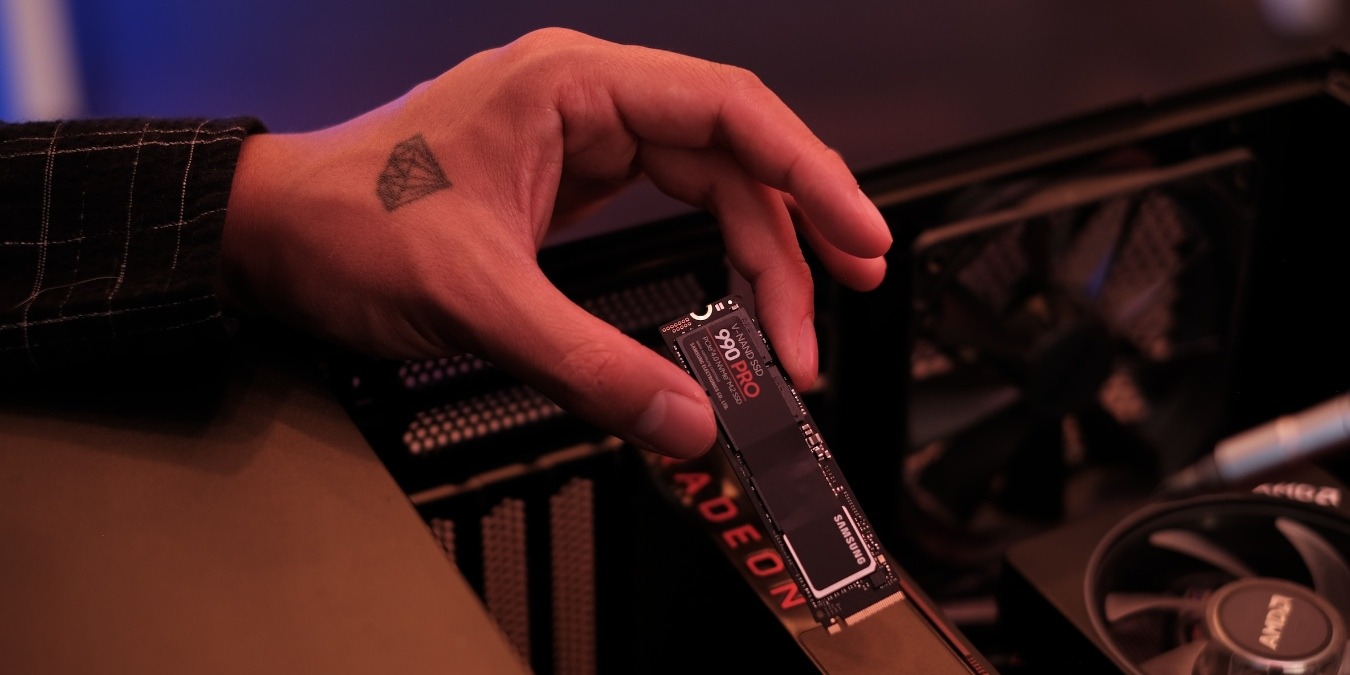 Hand holding a black Samsung SSD near an open PC
