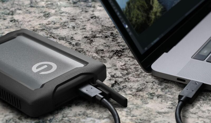 Seagate Professional G-DRIVE RmorATD 2TB Black and grey external hard drive on a marble surface next to a laptop