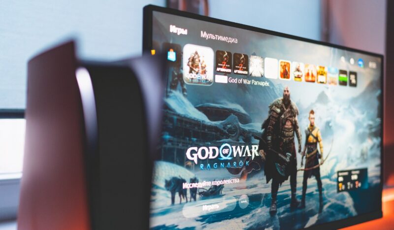 Close-up of PS5 with a TV in the background