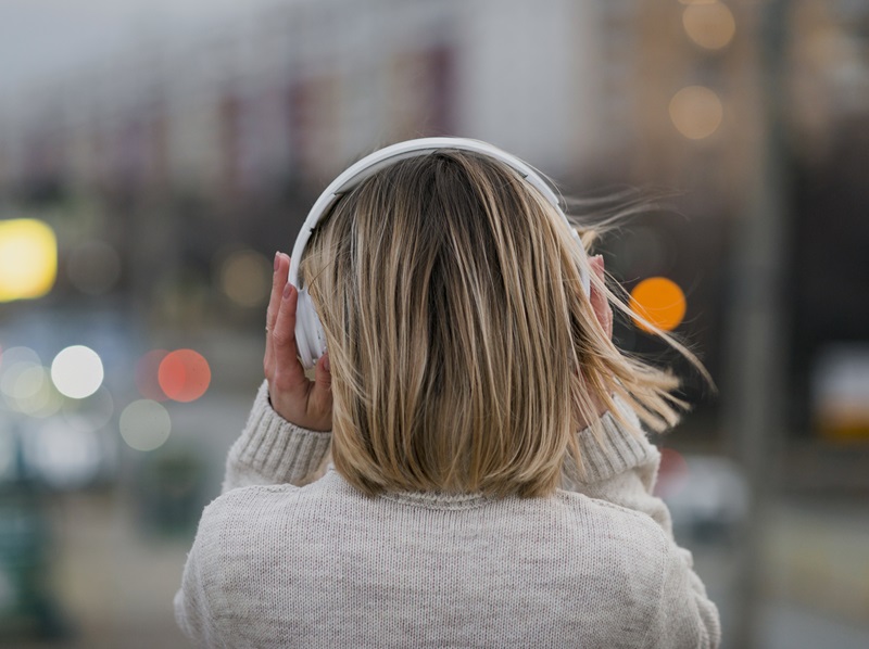 Woman wearing noise cancelling headphones outside.