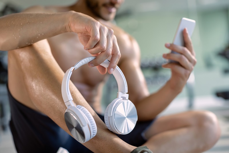 Man holding a pair of water-resistant headphones near pool. 