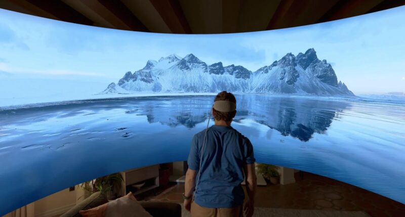 Person walking into the 180-degree panorama image of some icebergs. They are in the middle of the frame wearing an Apple Vision Pro headset.