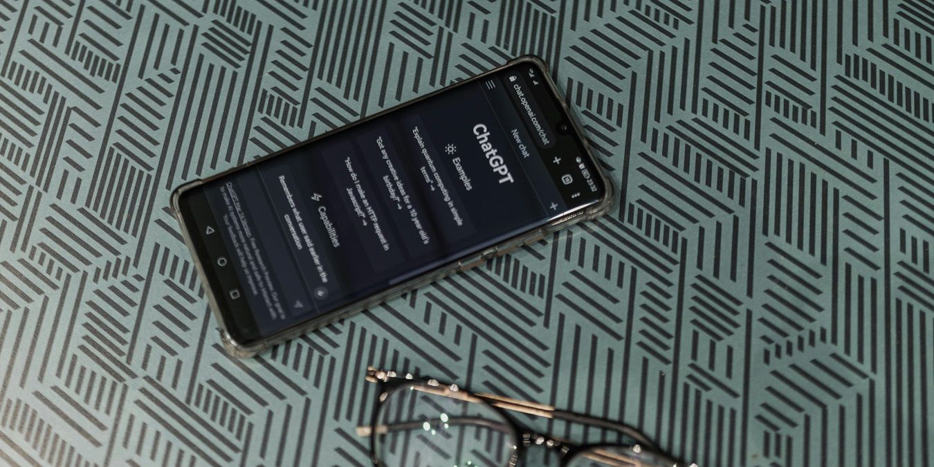 Phone running the ChatGPT app next to a pair of glasses.