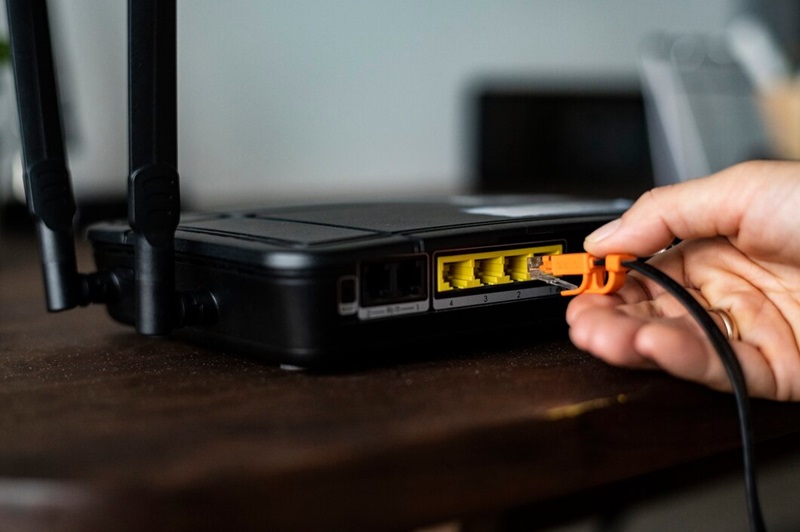 Man plugging ethernet cables inside a Wi-Fi router.