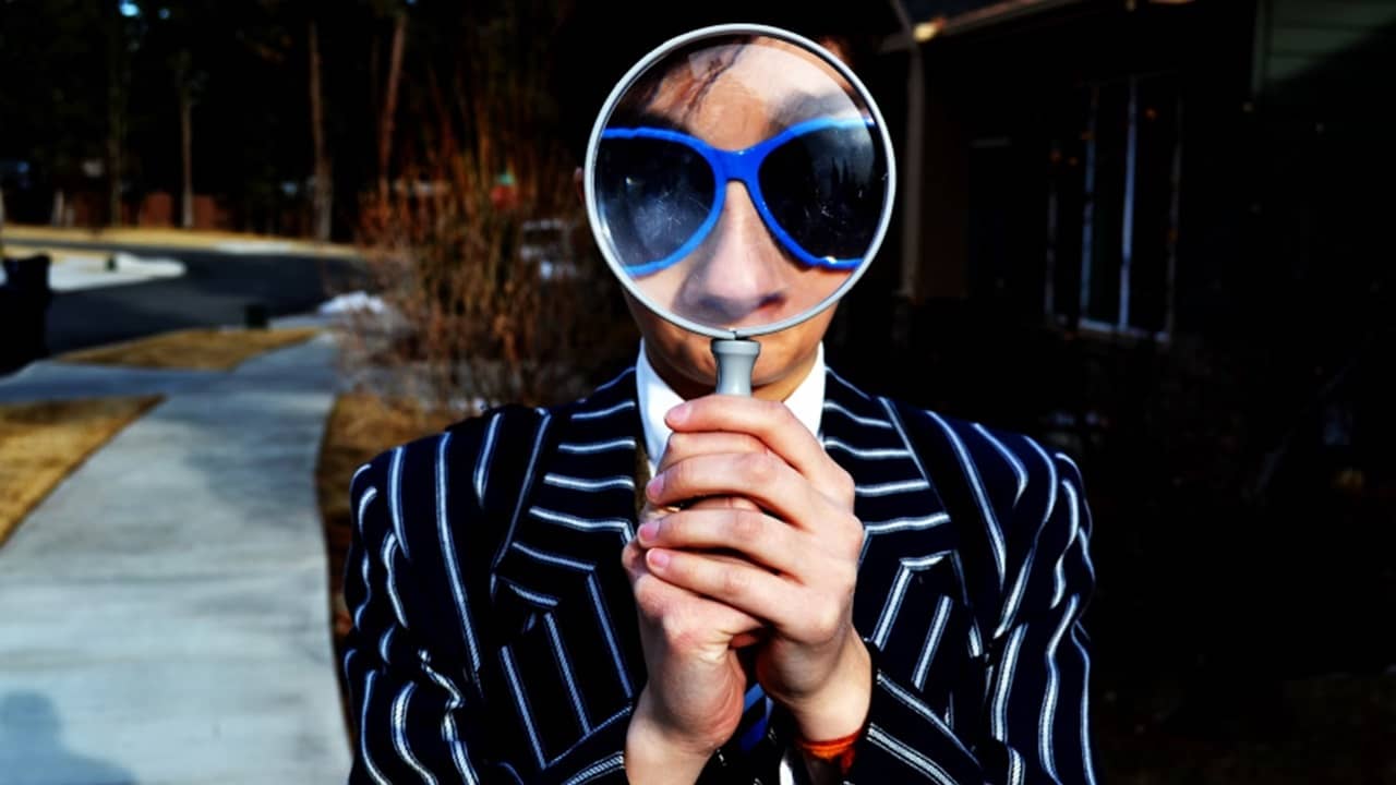 Person holding a magnifying glass in front of their face.