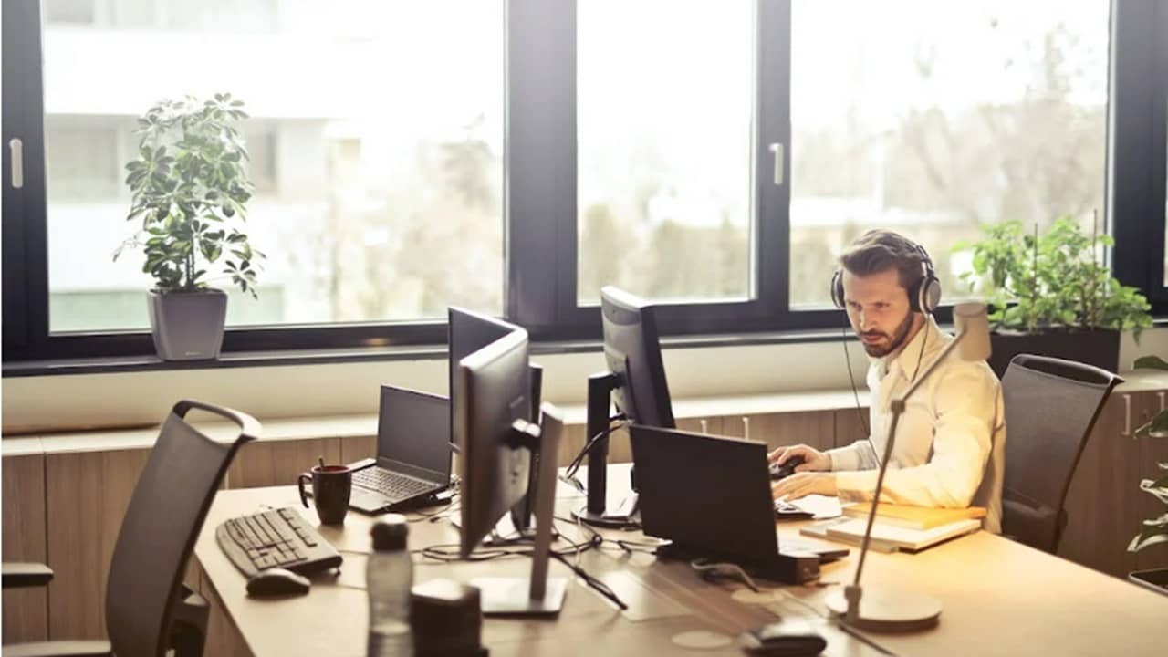 Man with headphones using a computer in an office.