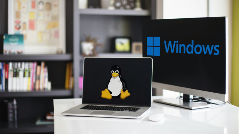 A photograph of a laptop and a computer monitor on top of a white desk.