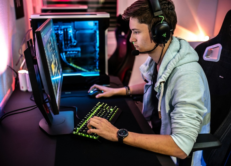 Person wearing headphones and playing on a gaming PC