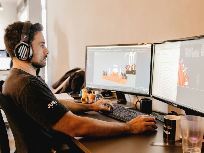 Person wearing headphones and using multiple monitors