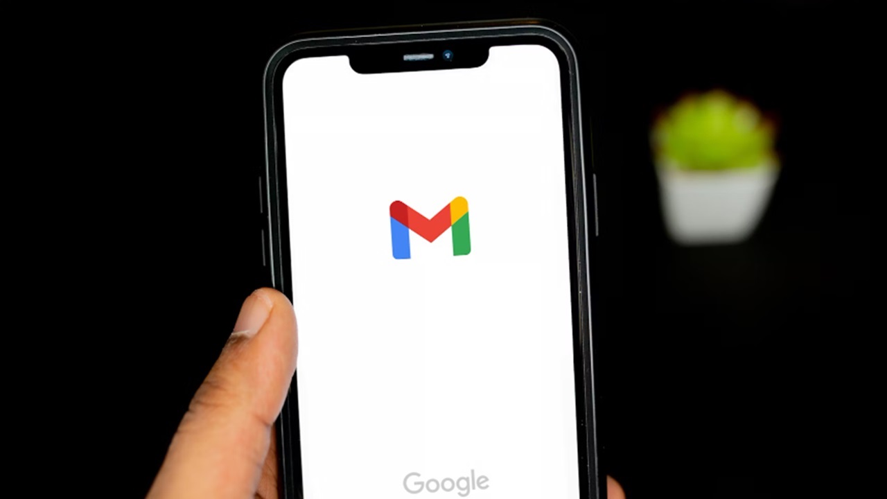 Hand holding a phone with Gmail logo.