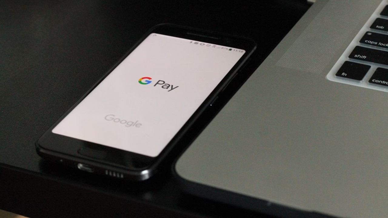 Google Pay opened on a phone next to a laptop.