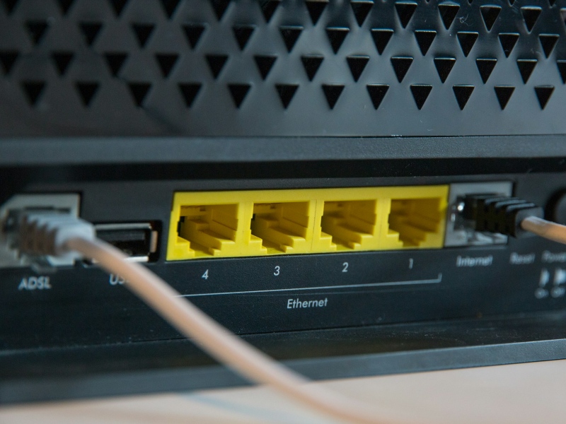 A close-up of a wireless router showing Ethernet ports and cables