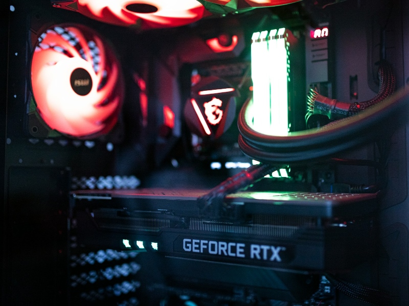 A gaming PC with a graphics card, RAM, and fans in RGB lighting