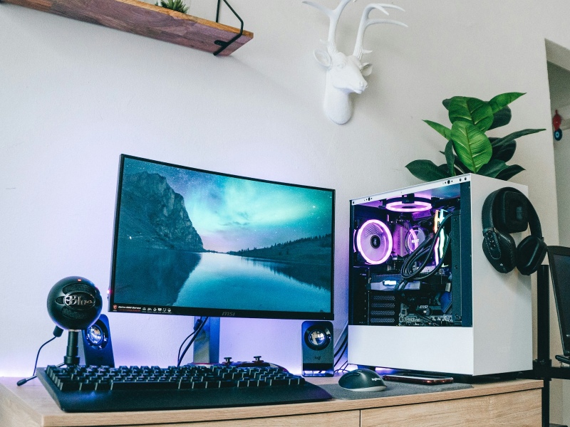 A gaming PC desk setup with a monitor, keyboard, mouse, and headphones