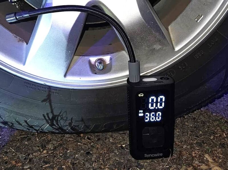 Syncwire tire inflator sitting next to a car tire.