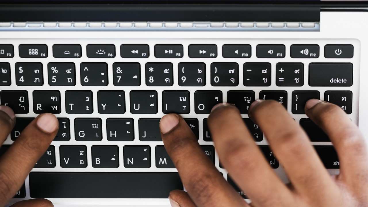 laptop keyboard with fingers on it