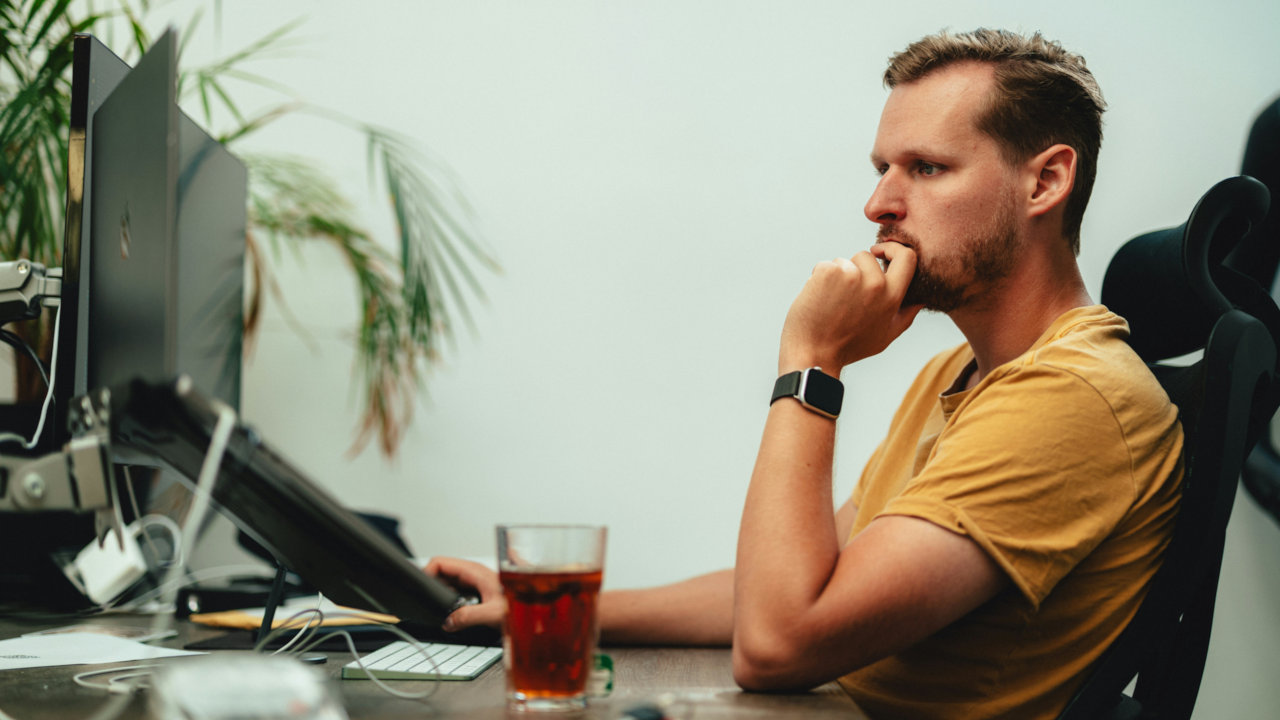 A photograph of a person working in front of a desktop computer.
