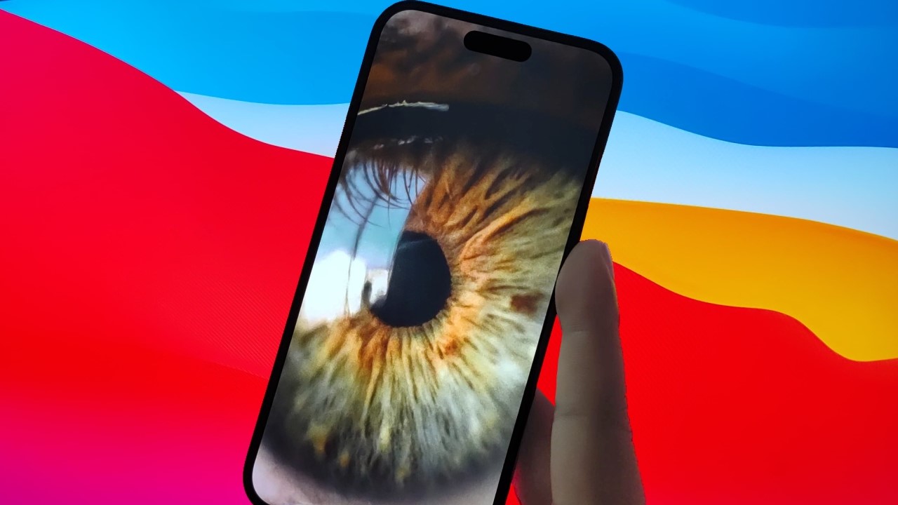 An image of an iPhone held against the background of a MacOS, with a picture of an eye displayed on the phone.