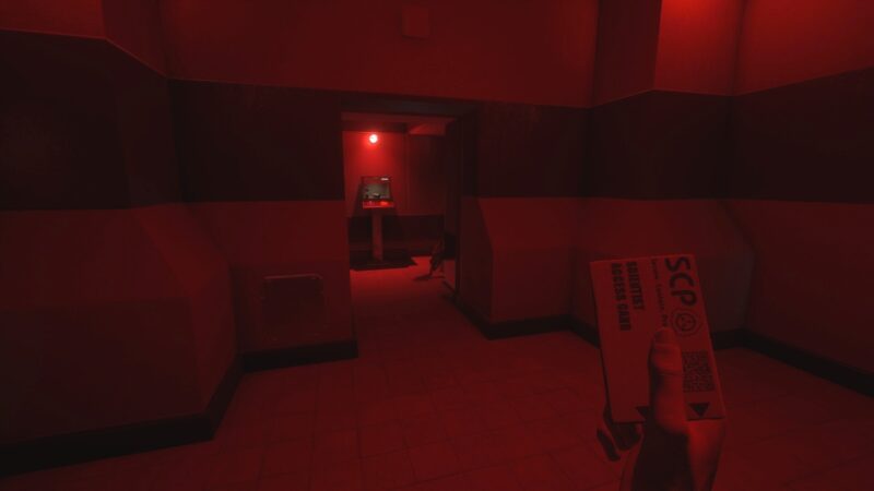 A screenshot from SCP: Secret Laboratory, showing a corridor flooded in red light, while the player holds up an ID-card saying 'SCP' in first-person view.