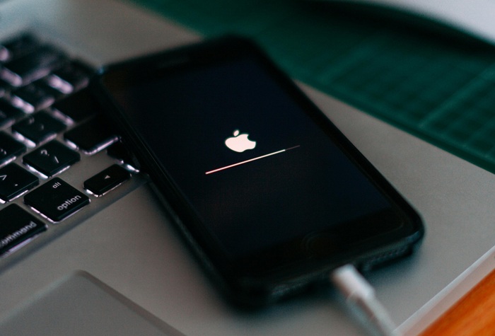 iPhone charging next to a MacBook device.