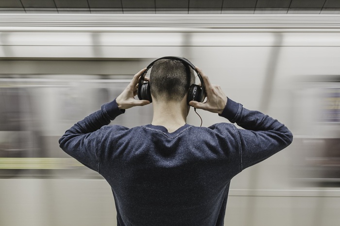 A man wearing a noise canceling headphone to block ambient sounds.