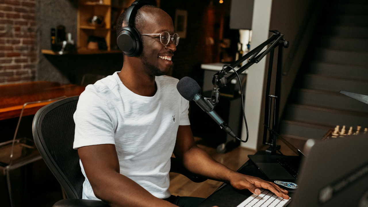 A photograph of a person with his headphone on in front of a computer.