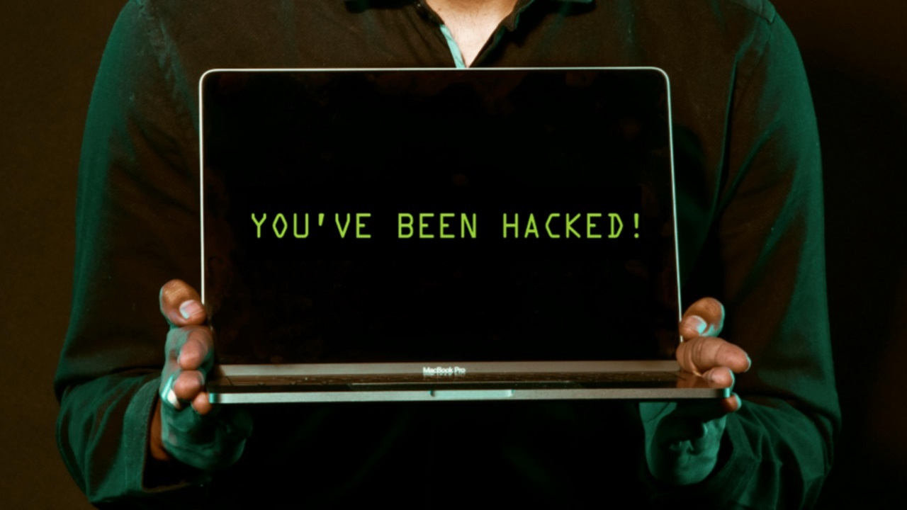 Man holding a laptop that says you've been hacked.