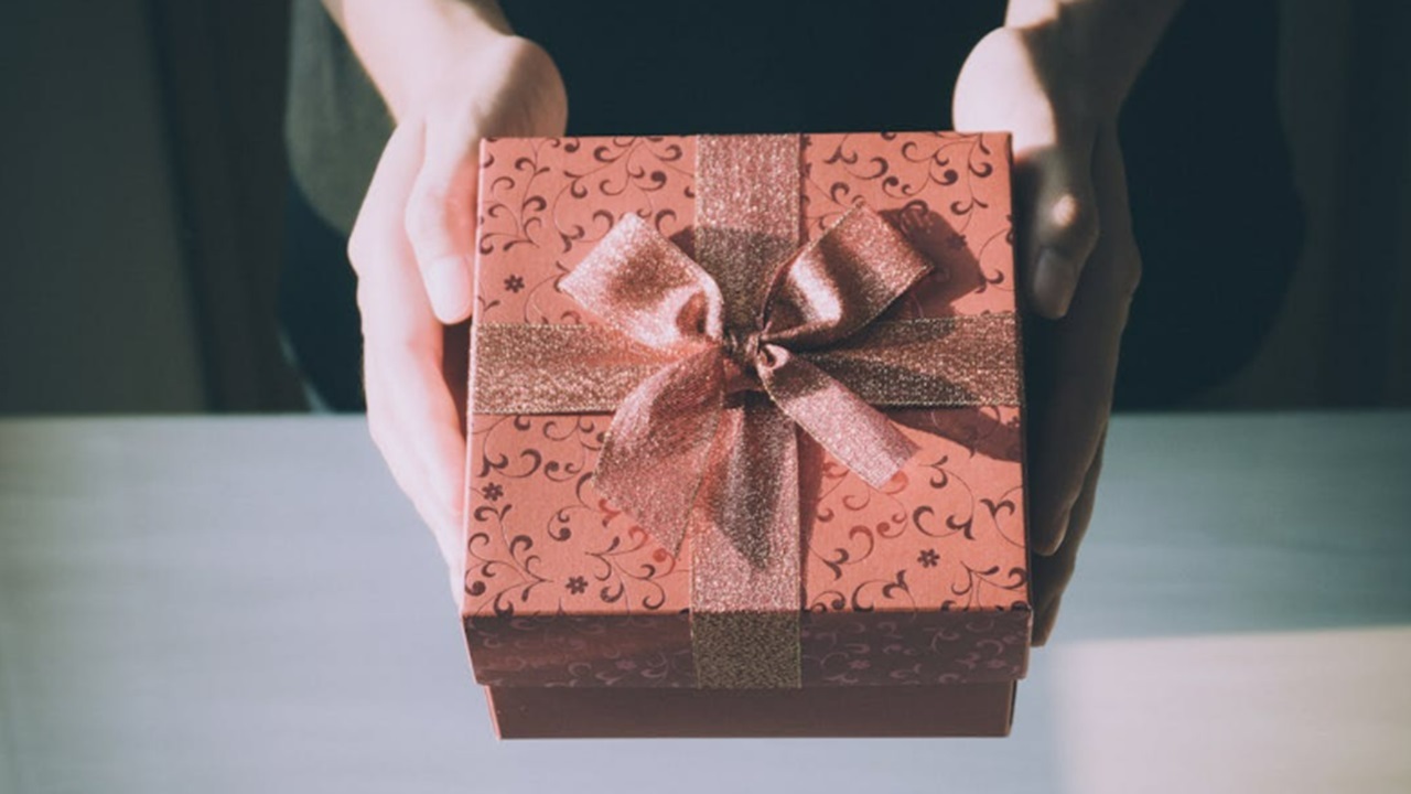 Hands offering a pink gift.