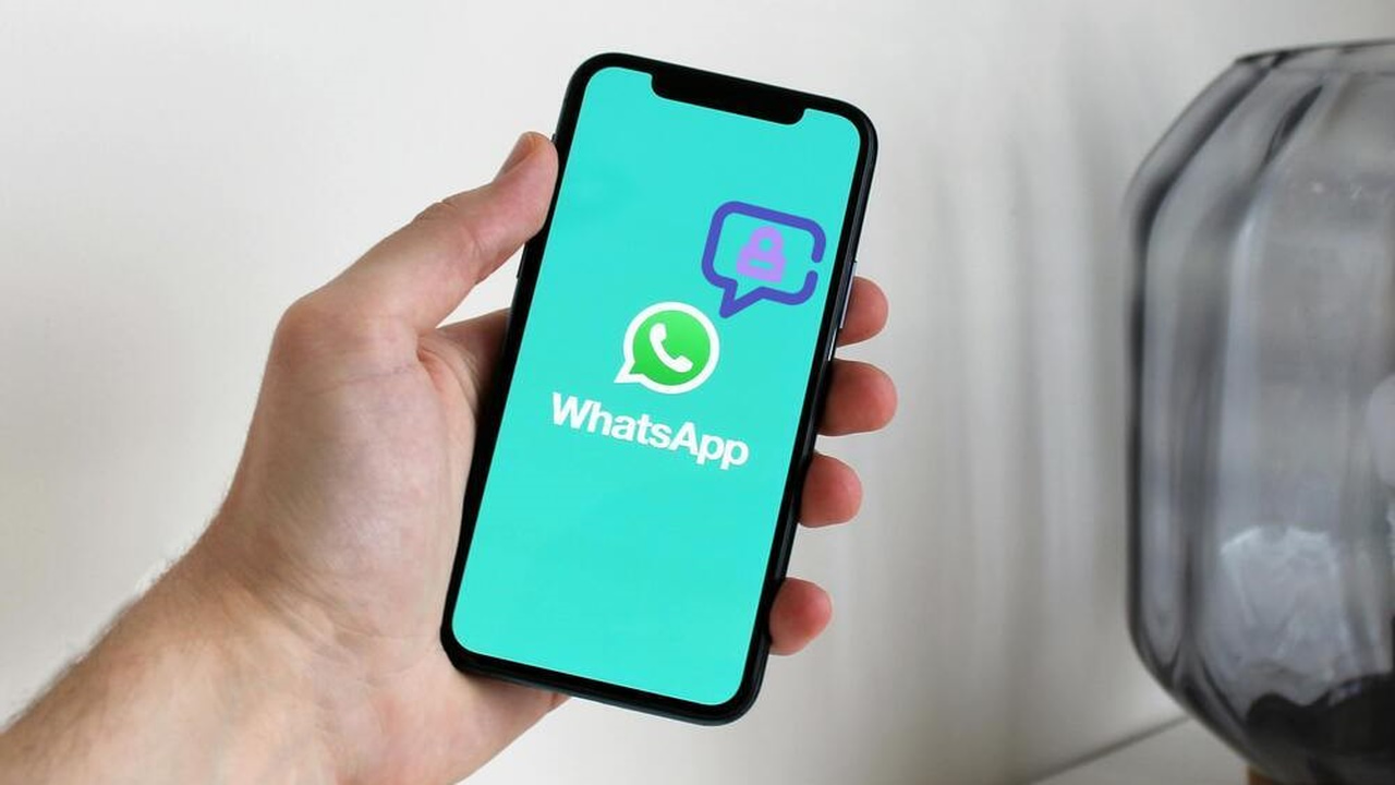 Man holding a phone with WhatsApp icon in middle