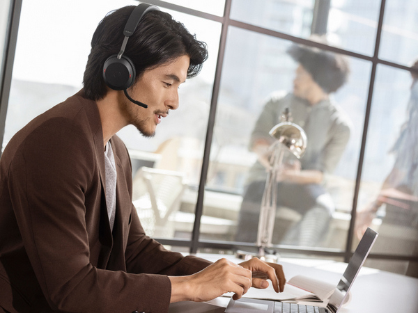 Man Wearing Jabra Evolve2 75 and using a laptop