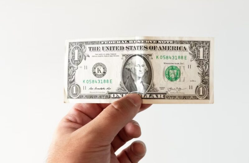 A hand holding a dollar bill.