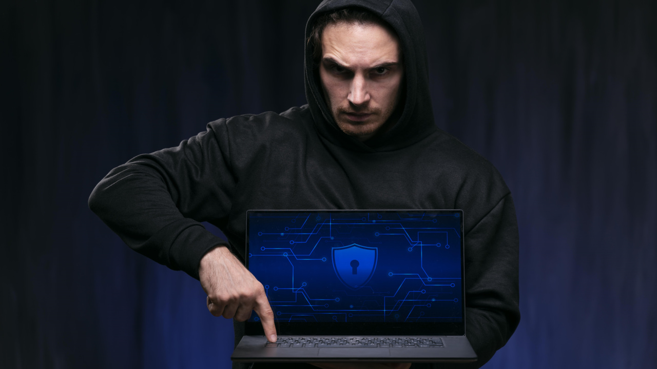 hacker man pointing at laptop keyboard